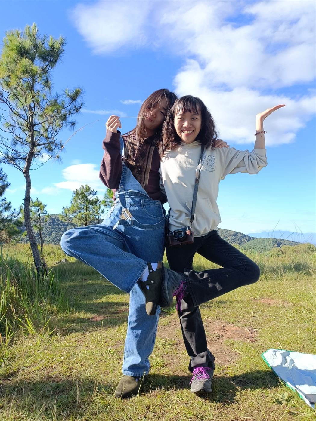 Two friends posing on the hill under a blue sky