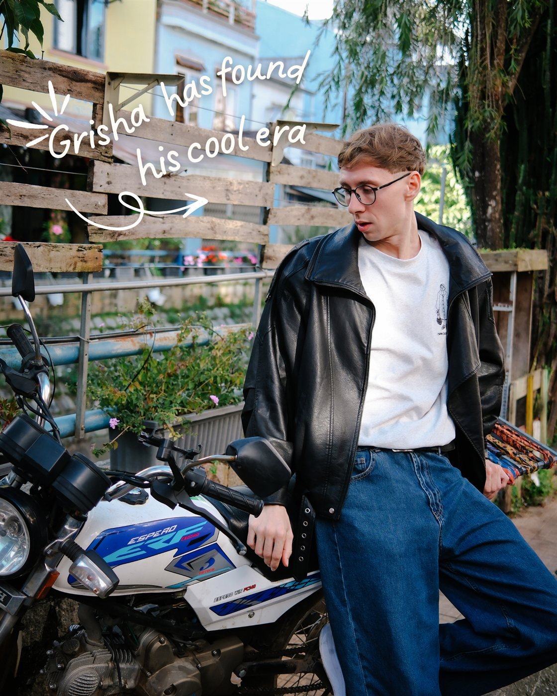 Grisha has found his cool era – posing with a motorbike by the river